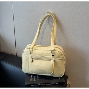 Detail of creamy yellow glossy leather shoulder bag with embossed logo and silver zipper