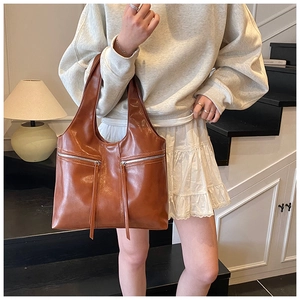 Détail d'un grand sac cabas vintage en cuir marron avec fermetures éclair et pompons longs