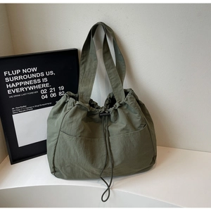 Close-up of olive green nylon tote bag with drawstring closure and front pocket detail
