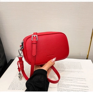 Dettaglio mini borsa a tracolla in pelle rossa martellata con ganci e nappa decorativa