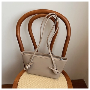 Détail du sac cabas beige verni avec nœud décoratif sur la bandoulière élégante