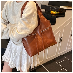 Détail du cabas vintage en cuir marron avec zips métalliques et longues languettes