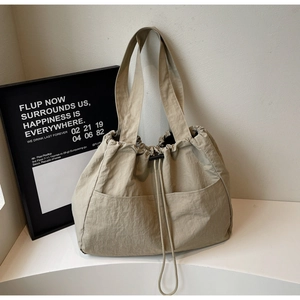 Detail of beige nylon tote bag with drawstring closure and large front pockets