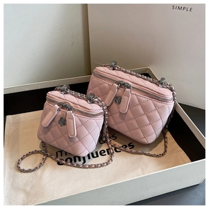 Close-up of pink quilted leather bags with silver chain straps and floral metal charms