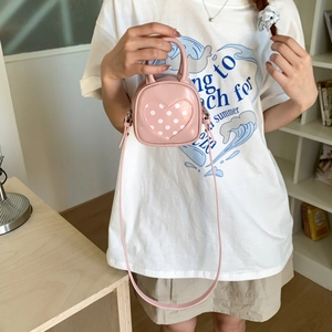 Detailed shot of pink mini bucket bag with heart polka dots and cylinder handle