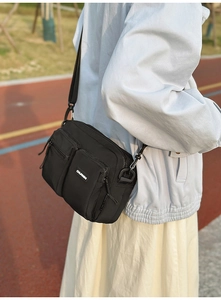 Détail du sac bandoulière en nylon noir avec plusieurs poches et une sangle réglable