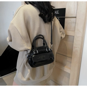 Rear view of a model wearing a mini black glossy leather pillow bag with silver hardware