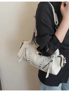 Sac à bandoulière vintage crème avec clous et finition brillante porté par le mannequin