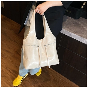 Détail d'un sac cabas en cuir beige avec poches zippées fonctionnelles et longues franges