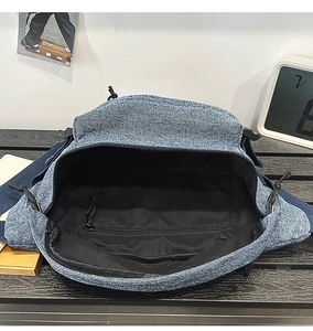 Internal view of blue denim sling bag showing black lining and hidden zipper pocket