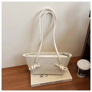 Détail du sac fourre-tout crème avec bandoulière nouée et fermeture éclair sur un bureau
