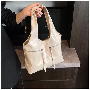 Détail d'un sac à bandoulière crème brillant en similicuir avec des fermetures éclair en métal