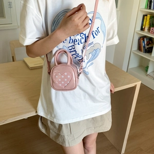 Pink heart-shaped crossbody bag with white polka dots and adjustable shoulder strap