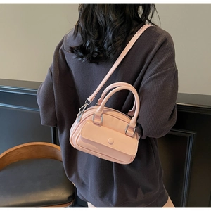 Detailed back view of a pink mini crossbody pillow bag worn by a model in soft light