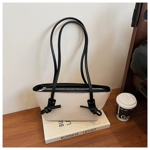 Détail du sac cabas bicolore avec bandoulières à double nœud et accessoires de mode