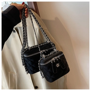 Detail der schwarzen Stepptasche mit doppelten Ketten und Blumen-Reißverschluss-Anhängern