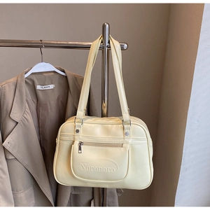 Detailed view of beige leather tote bag featuring a front zipper pocket and embossed logo