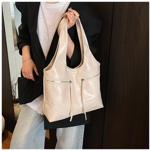 Détail du sac hobo crème en cuir poli avec de longues fermetures éclair à franges déco