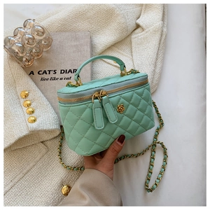 Detalle del bolso tipo cubo acolchado verde menta con cierre floral de metal en oro camelia