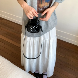 Detail of heart-shaped black polka dot mini crossbody bag with a slim strap and zipper