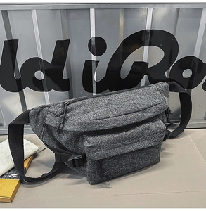 Detail view of washed denim chest bag with adjustable nylon strap and utility pockets