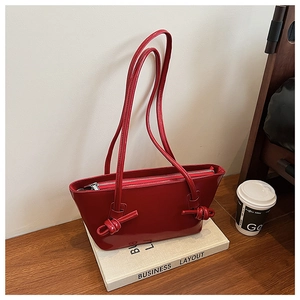 Détail du sac cabas en cuir verni rouge avec bandoulière nouée et fermeture éclair