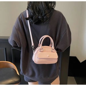 Detail of pink pillow bag featuring smooth faux leather and a small front flap pocket