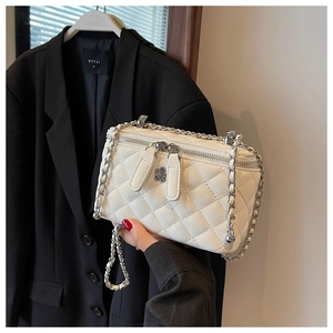 Detailaufnahme der weißen Stepptasche mit silbernen Reißverschlüssen und Kamelien-Charm