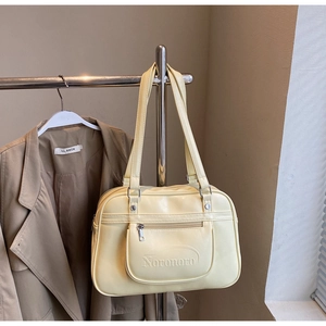 Close-up of cream PU leather handbag with zipper pocket and metal brand logo detail