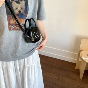 Detail of a black heart polka dot mini PU leather bucket bag styled with a white skirt