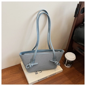 Détail du sac cabas bleu clair montrant les sangles nouées et la texture tissée fine