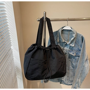 Detail view of large waterproof nylon tote with drawstring closure and front pockets