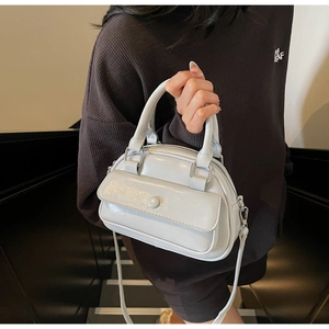 Detail of glossy patent leather mini bag with front flap pocket and decorative buckle