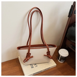 Détail d'un sac cabas en toile avec poignée en cuir marron nouée et fermeture éclair