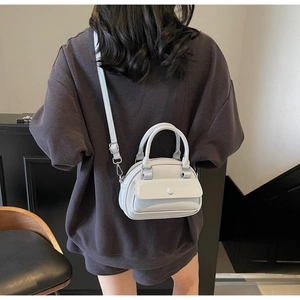 Rear view of a model wearing a light gray patent leather bowling bag with thin strap