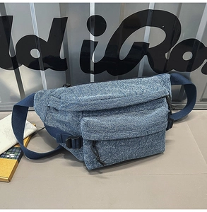 Close-up of blue washed denim waist bag with adjustable strap and front zipper pocket