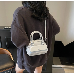 Detail showing a light blue Boston bag worn crossbody over an oversized sweatshirt