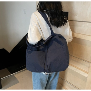 Detail of navy blue nylon tote bag showing drawstring pockets and large capacity