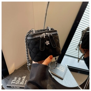Detail der schwarzen gesteppten Ketten-Vanity-Bag mit Kamelien-Metall-Charm und Silberkette