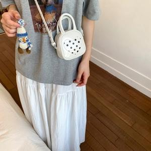 Detailed view of white PU leather bucket bag featuring a polka dot heart and penguin charm