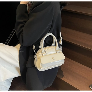 Close-up of cream white glossy leather handbag with magnetic flap on wooden stairs