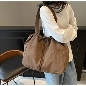 Detail of large brown nylon tote bag with drawstring pockets and double shoulder straps