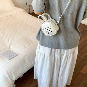 Detail of a white heart-shaped crossbody bag with polka dot pattern on a model