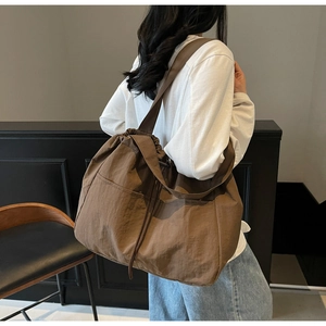 Detail of a brown pleated tote bag with large capacity and drawstring closure for women
