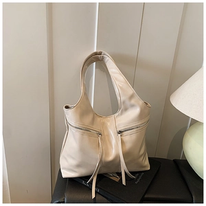 Gros plan détaillé d'un sac cabas en similicuir crème avec de longs zips à glands