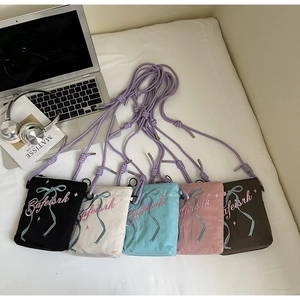Detail view showing five colors of canvas phone bags with ribbon embroidery and rope straps