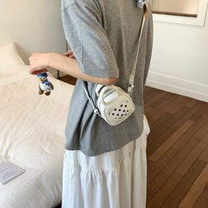 White heart-shaped crossbody bag with black polka dots and a cute penguin charm detail