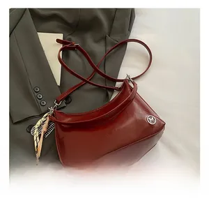 Detail showing wine red glossy faux leather tote bag with metal M logo and scarf charm