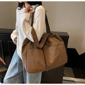 Brown large capacity tote bag with drawstring closure and large front pockets on model