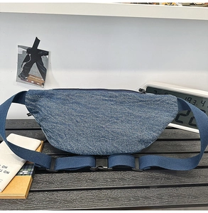 Detailed macro view of deep blue denim fabric texture and black zipper on crossbody bag